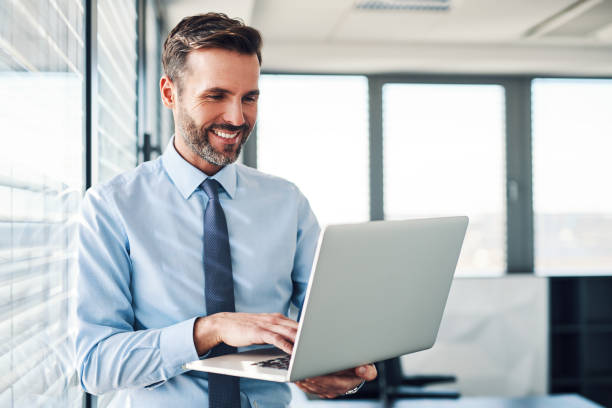 Handsome businessman in modern office looking on laptop